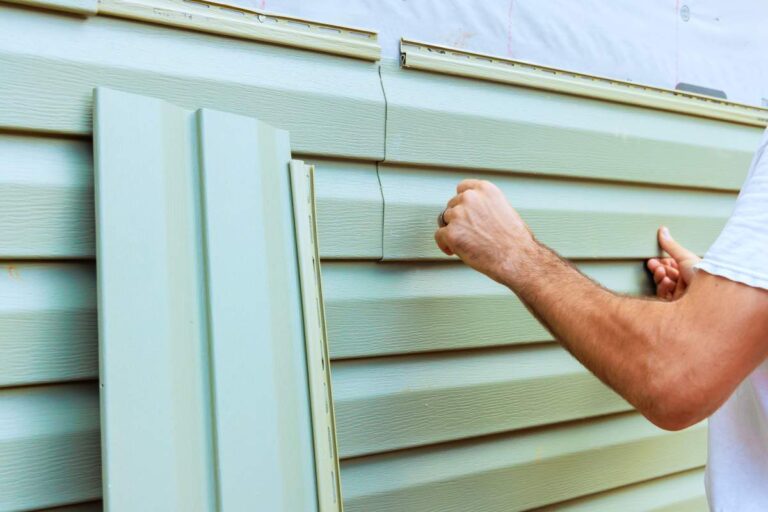 A close-up view of various siding materials installed side by side on exterior house walls.